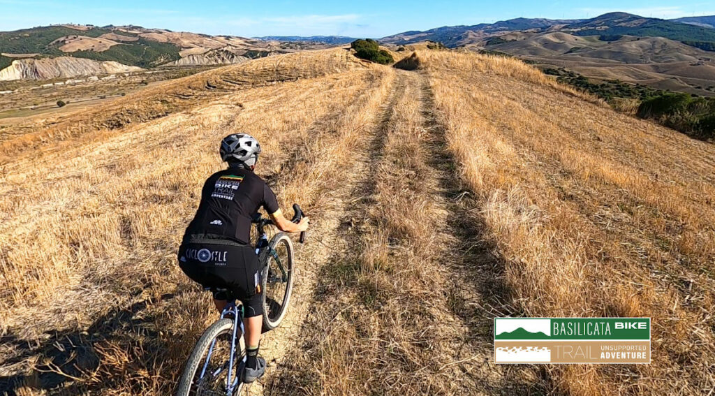 Ciclista in esplorazione con bicicletta gravel su un tipico sentiero sterrato della Lucania.