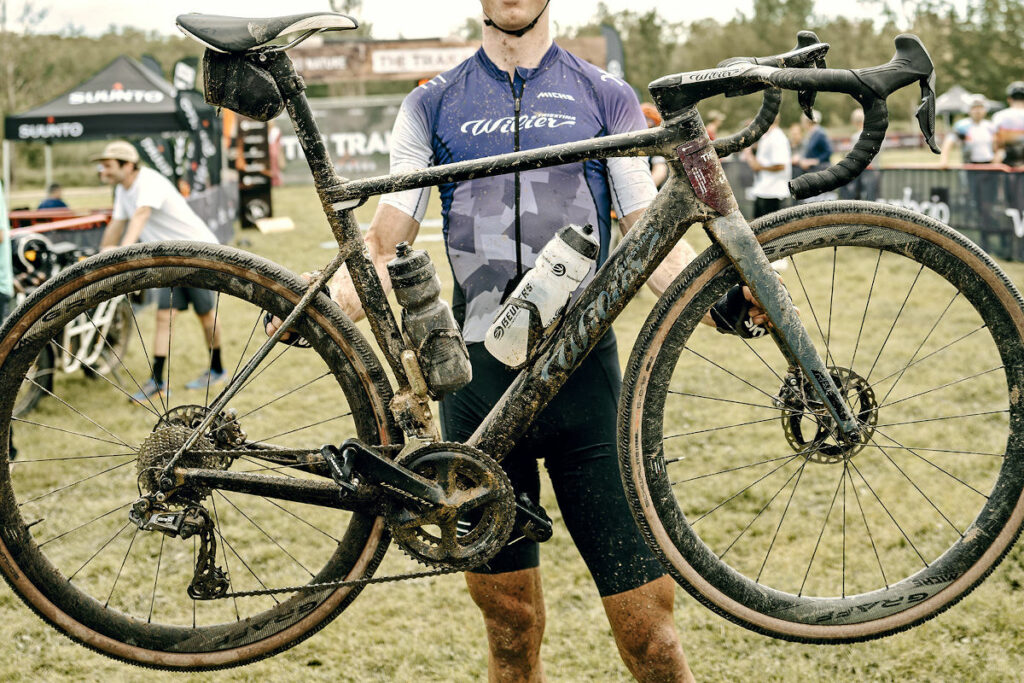 Un atleta esibisce la bicicletta gravel di alta gamma dopo una competizione offroad.